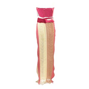May include: A crochet two-piece outfit with a pink and cream striped skirt and a matching pink crop top.