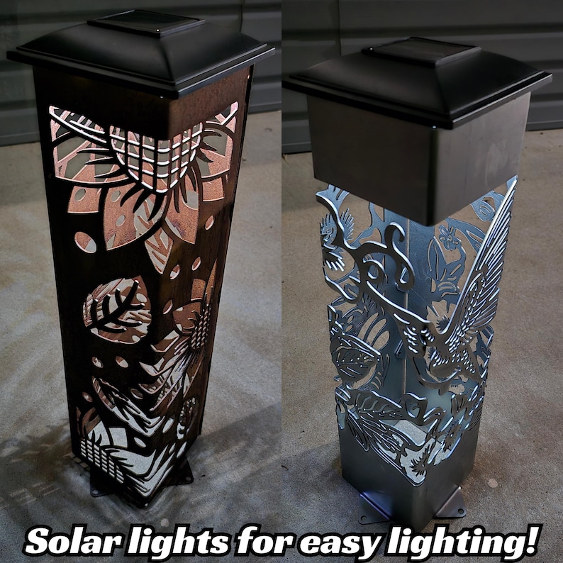 Two solar garden posts at night: one illuminated with intricate cutout patterns, the other unlit with detailed steel designs.