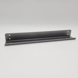 May include: A gray metal shelf with a textured finish and rounded edges. The shelf is designed to be mounted on a wall.