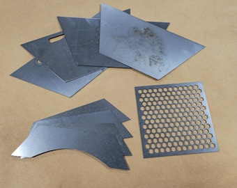 May include: A set of metal sheets in various shapes and sizes, including a sheet with a honeycomb pattern. The sheets are grey and have a metallic finish.