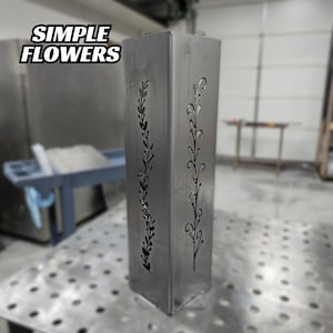 Metal garden post featuring a minimalist floral cutout design, displayed in a workshop.