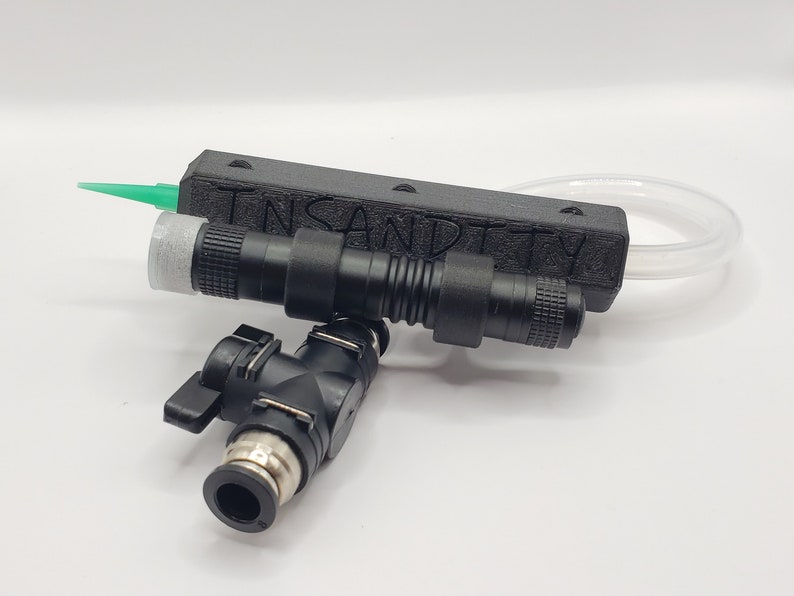 May include: A black and green airbrush system with a clear tube and a black valve. The system has the text "INSANDITY" printed on it.