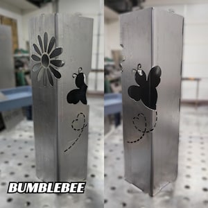 Metal garden post with a bumblebee and flower cutout design in a workshop setting.