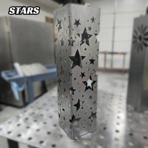 Metal garden post with star-shaped cutout design in a workshop setting.