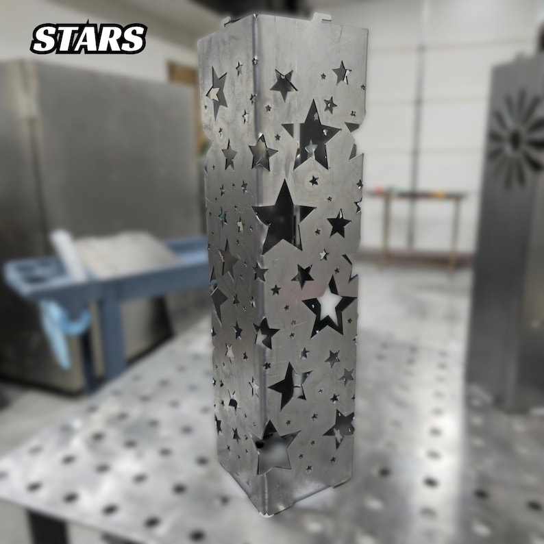 Metal garden post with star-shaped cutout design in a workshop setting.