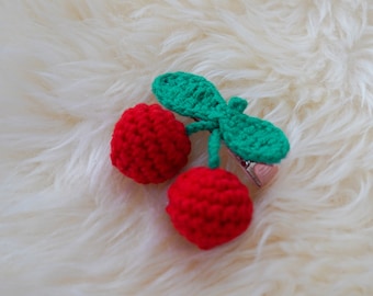 Puede incluir: Una pinza para el pelo de cereza de crochet rojo y verde. La cereza está hecha de dos bolas rojas con una hoja de crochet verde en la parte superior.
