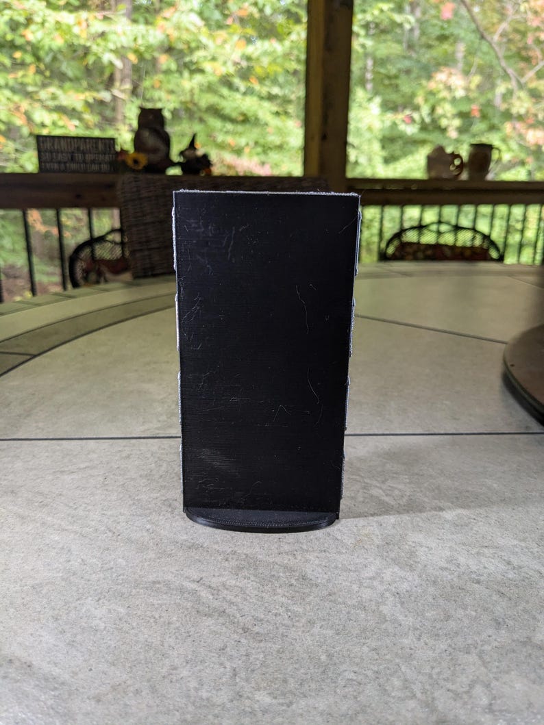 May include: A black chalkboard sign with a rounded base. The sign is blank and ready to be written on.