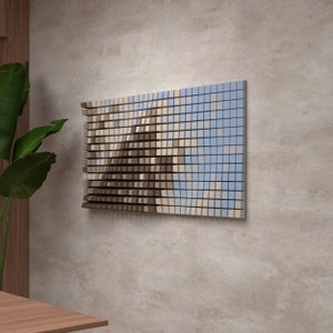 Op de afbeelding: Een wandkunstwerk gemaakt van kleine vierkanten in tinten bruin, beige en blauw. De vierkanten zijn in een golvend patroon gerangschikt, waardoor een modern en abstract ontwerp ontstaat.