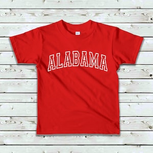 May include: Red short-sleeved t-shirt with white text that reads "ALABAMA" in a collegiate font.
