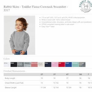 Op de afbeelding: Een grijs fleece crewneck sweatshirt voor peuters met een maattabel die de afmetingen in inches aangeeft. De trui is verkrijgbaar in verschillende kleuren, waaronder wit, zwart, grijs en rood.