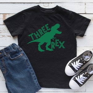 Könnte beinhalten: Schwarzes T-Shirt mit einem grünen Dinosaurier-Motiv und dem Text "THREE REX".
