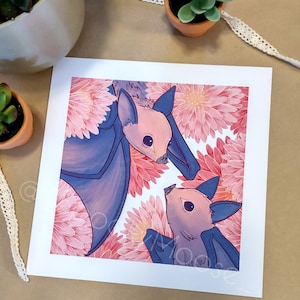 May include: Two pink bats with blue wings are nestled amongst pink and white flowers. The bats have large eyes and are looking at each other.