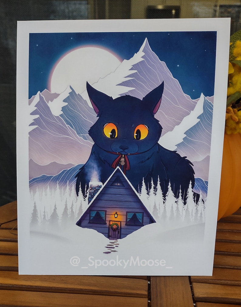 May include: A digital illustration of a large black cat with glowing yellow eyes standing in front of a small wooden cabin in a snowy mountain landscape. The cat is wearing a red ribbon around its neck with a bell attached. The moon is visible in the night sky.