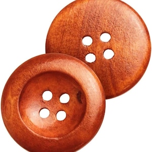 Könnte beinhalten: Zwei große, runde Holzknöpfe mit warmbraunem Finish. Jeder Knopf hat vier gleichmäßig verteilte Löcher zum Annähen. Die Knöpfe liegen eng beieinander und zeigen die natürliche Holzmaserung und -struktur.