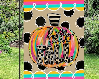 May include: A colourful, abstract pumpkin with black polka dots and the text "hello fall" on a brown background with colourful stripes. The design is for a garden flag.