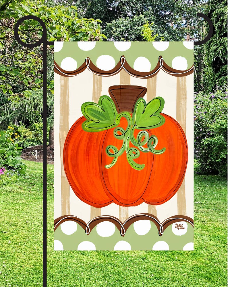 May include: A rectangular garden flag featuring a central orange pumpkin with a brown stem and green leaves. The background has vertical beige stripes, framed by top and bottom borders of light green with white polka dots and brown scalloped lines.