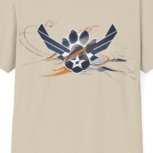 May include: A beige t-shirt with a graphic print of a paw print inside a stylized military wing design. The graphic is in shades of blue and orange.