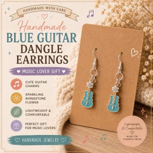 May include: A pair of dangle earrings featuring blue guitar charms and silver-toned flower accents with clear rhinestones. The earrings are attached to a brown rectangular display card. The text on the card reads Handmade Blue Guitar Dangle Earrings.