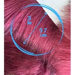 May include: Close-up of a burgundy faux fur fabric. The fur is approximately 3 inches in length. The image includes a blue circle with measurements and the brand name "LAMBZY".