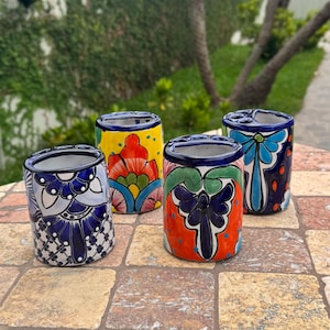May include: Four colorful ceramic toothbrush holders with intricate floral designs. The holders feature a variety of colors, including blue, yellow, red, and green. Each holder has a unique pattern and design, perfect for bathroom decor.