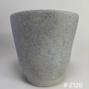 May include: A ceramic cup featuring a white base with a dark gray crackle glaze pattern covering the exterior surface. The cup has a tapered shape and a smooth, unglazed white foot. The text # 2128 is visible in the bottom right corner.