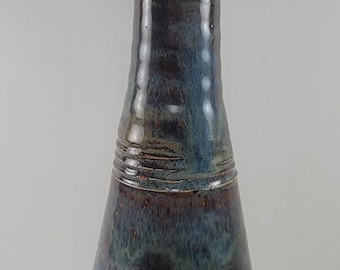 May include: A ceramic oil bottle with a stainless steel spout. The bottle has a dark blue, brown, and green glaze. The bottle has a unique shape and is marked with the number #2844.