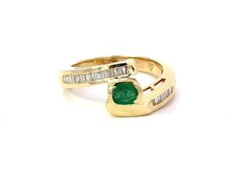 May include: A gold ring with a green emerald gemstone and baguette-cut diamonds. The ring has a unique, twisted design.