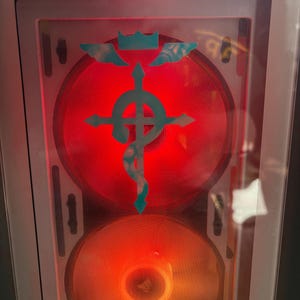 An example of the Flamel Cross decal in white placed over a transparent computer tower, with changing LED lights glowing behind it.