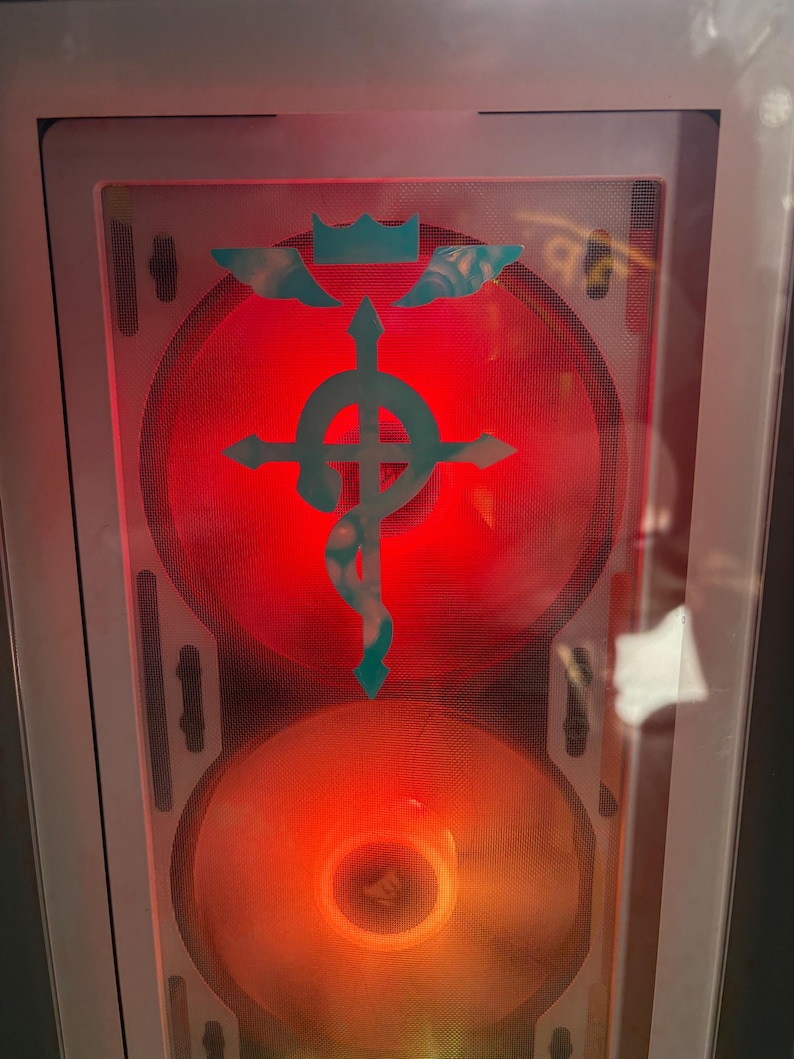 An example of the Flamel Cross decal in white placed over a transparent computer tower, with changing LED lights glowing behind it.