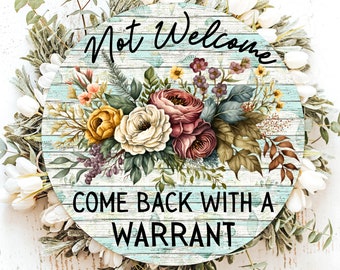 Könnte beinhalten: Runder Holzschild mit dem Text "Not Welcome Come Back With A Warrant". Das Schild hat einen Hintergrund aus blauem Holzmaserung und ist mit einem Blumenarrangement aus Rosen und anderen Blumen verziert.