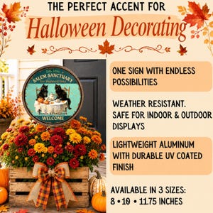 May include: A round metal sign featuring two black cats sitting at a table with pumpkins, labeled Salem Sanctuary for Wayward Cats, Est. 1692. The sign is displayed in a wooden crate filled with orange, yellow, and red chrysanthemums and pumpkins.