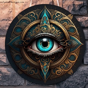 May include: A circular wall hanging with a large, blue eye surrounded by intricate gold and teal designs. The eye is set against a black background.