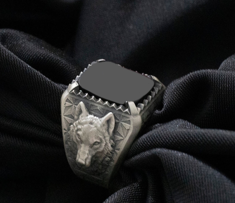 Puede incluir: Un anillo de plata con una piedra negra y un dise&ntilde;o de cabeza de lobo.