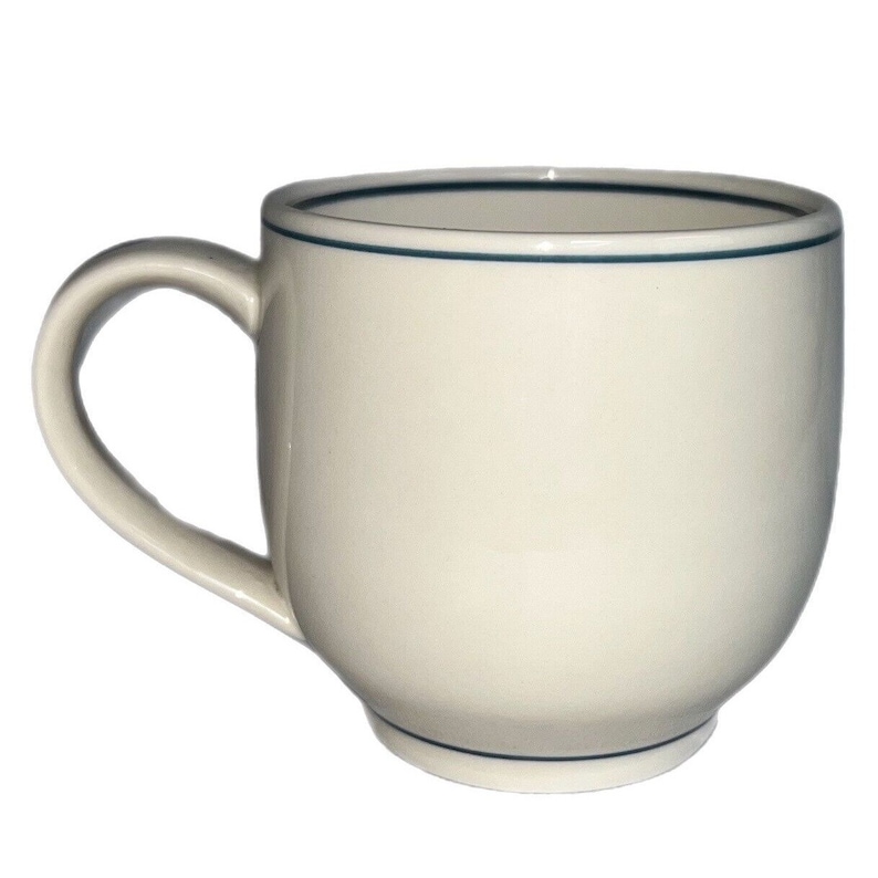 May include: A white ceramic mug with a blue rim. The mug has a rounded body and a handle.