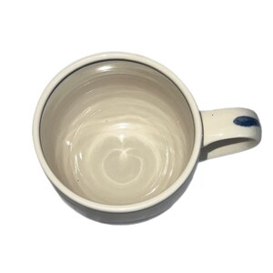 May include: A white ceramic mug with a blue rim and a blue stripe on the handle. The mug has a swirl pattern inside.
