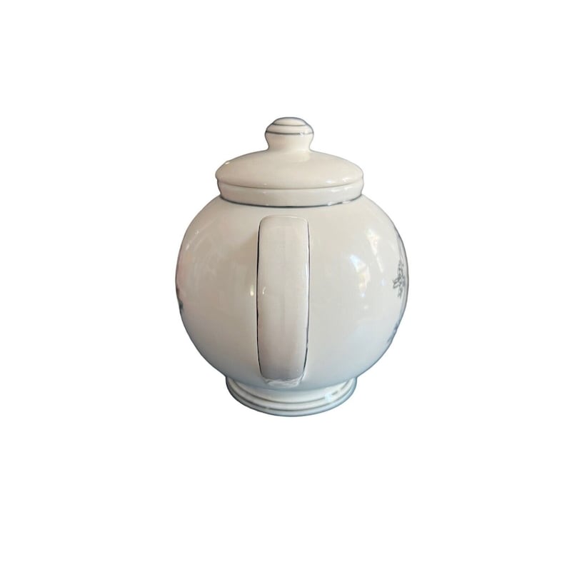 May include: A white ceramic teapot with a rounded body and a matching lid. The teapot has a handle and a spout, and is decorated with a subtle floral pattern. The rim and handle are trimmed with a thin silver line. The teapot is designed for brewing tea.