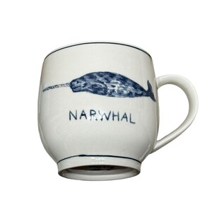 May include: White ceramic mug with a blue and black narwhal illustration and the word "NARWHAL" printed on the front.