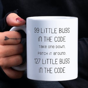 May include: White ceramic mug with black text that reads "99 LITTLE BUGS IN THE CODE Take one down, Patch it around. 127 LITTLE BUGS IN THE CODE"