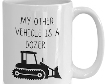 May include: White ceramic coffee mug with a black silhouette of a bulldozer and the text "My other vehicle is a dozer."