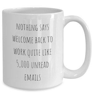May include: White ceramic coffee mug with black text that reads "Nothing says welcome back to work quite like 5,000 unread emails".
