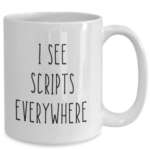 May include: White ceramic coffee mug with black text that reads "I see scripts everywhere".