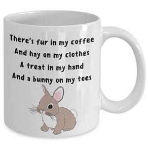 May include: White ceramic mug with black text: "There's fur in my coffee, And hay on my clothes, A treat in my hand, And a bunny on my toes." A cartoon bunny illustration is also on the mug.
