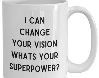 Peut inclure: Une tasse à café en céramique blanche avec du texte noir qui dit "Je peux changer votre vision quelle est votre superpuissance ?"