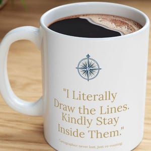 May include: A white ceramic mug filled with black coffee. The mug features a blue compass rose graphic above the gold text: "I Literally Draw the Lines. Kindly Stay Inside Them." and the smaller text: "Cartographer: never lost, just re-routing."