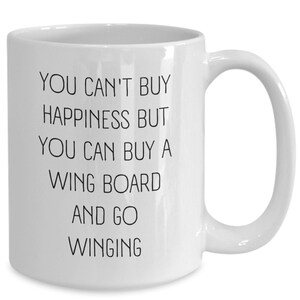 Peut inclure: Une tasse à café en céramique blanche avec du texte noir qui dit "Vous ne pouvez pas acheter le bonheur mais vous pouvez acheter une planche à voile et aller faire du wingfoil."