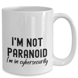 May include: White ceramic coffee mug with black text that reads "I'm not paranoid I'm in cybersecurity".