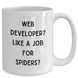 May include: White ceramic coffee mug with black text that reads "WEB DEVELOPER? LIKE A JOB FOR SPIDERS?"