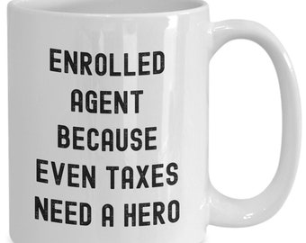 May include: White ceramic coffee mug with black text that reads "Enrolled Agent Because Even Taxes Need A Hero".