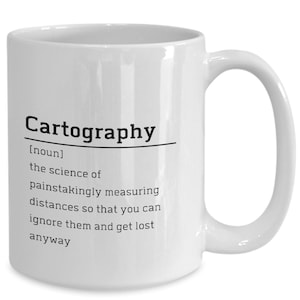 May include: White ceramic coffee mug with a black graphic that says "Cartography [noun] the science of painstakingly measuring distances so that you can ignore them and get lost anyway."