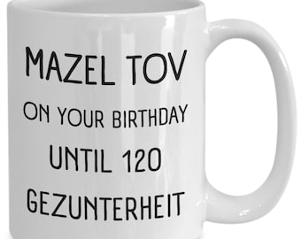 May include: White ceramic coffee mug with black text that reads "Mazel Tov on your birthday until 120 Gezundheit".